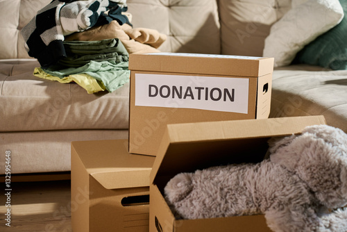 Obraz na płótnie Donation boxes filled with clothes and stuffed toy on couch. Charity and community aid concept w salonie