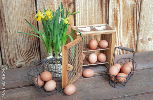 chicken eggs  in little metal baskets and a decorative box on a table with a ...