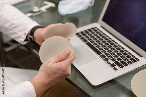 A plastic surgeon holds breast implants in his hands