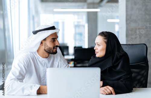Photography Handsome man and woman with traditional clothes working in an office of Dubai