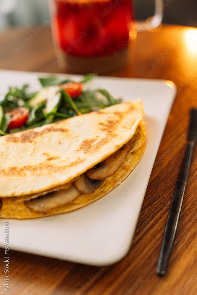 Tortilla with champignons with salad in a square white plate. Tortilla with champignons with salad in a square white plate.