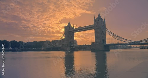 Timelapse of Tower Bridge in London at Sunrise with the Sun Rising Behind the Bridge and Vibrant Sky Reflections on the River Thames.
