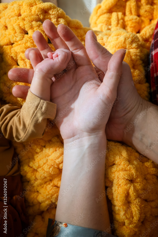 Adult and Baby Hand on Yellow Knitted Blanket