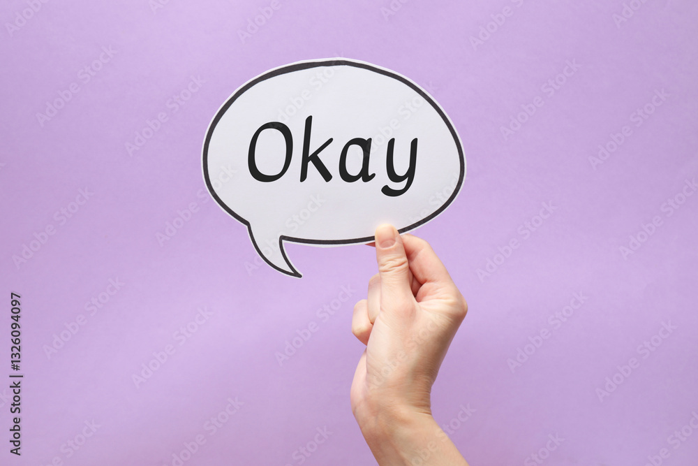 Woman holding paper speech bubble with word Okay on lilac background, closeup Woman holding paper speech bubble with word Okay on lilac background, closeup