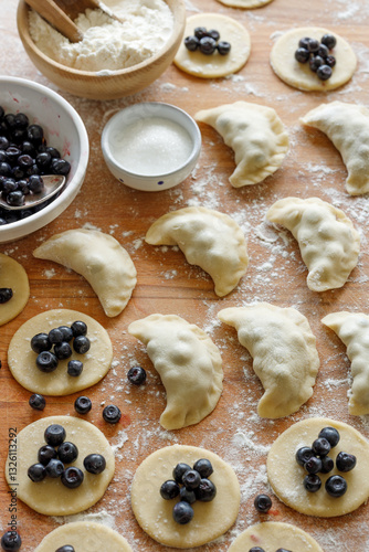 Homemade sweet pierogi, dumplings  filled with fresh blueberries during the preparation process, close up view. Traditional polish food.