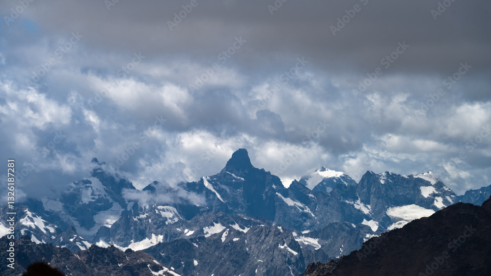Fototapeta premium snowy mountain peaks in the clouds