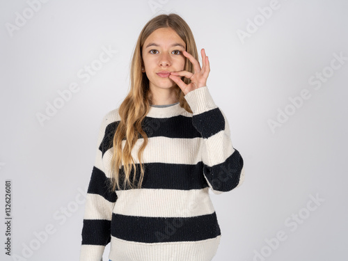 beautiful caucasian teen girl wearing striped sweater mouth and lips shut as zip with fingers. Secret and silent, taboo talking.