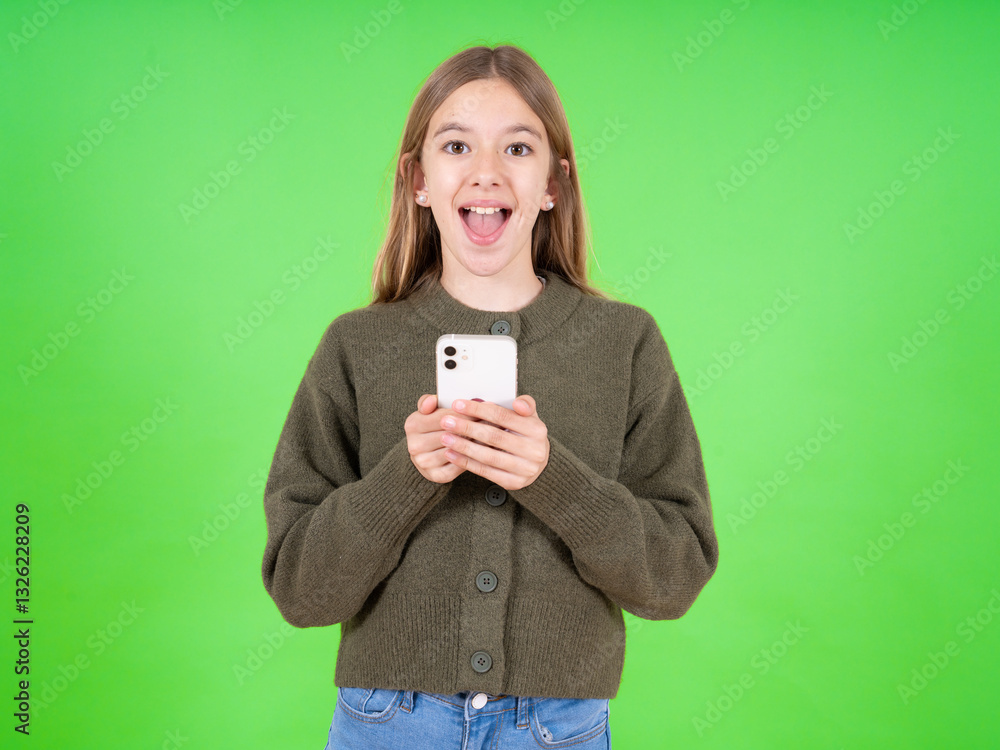Excited beautiful caucasian girl wearing green sweater holding smartphone and looking amazed to the camera after receiving good news. Excited beautiful caucasian girl wearing green sweater holding smartphone and looking amazed to the camera after receiving good news.