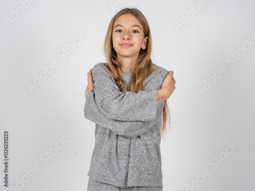 Obraz na plátně Charming pleased beautiful caucasian girl wearing grey track-suit embraces own body, pleasantly feels comfortable poses