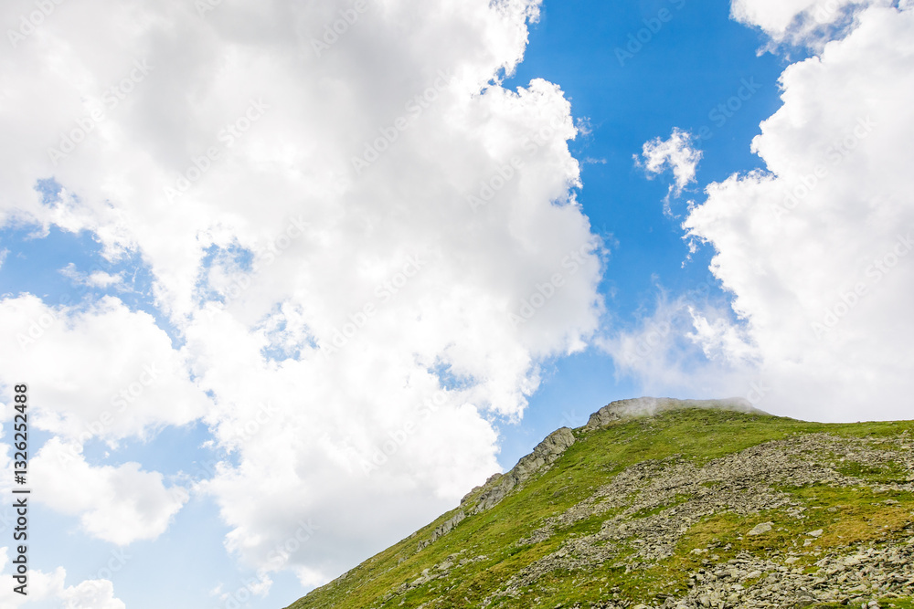 landscape with mountain and blue sky with clouds. scenic view. steep hill with stones and grass. beautiful nature of romania in summer