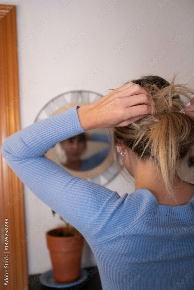 Naklejka premium woman touching up her hair in front of a mirror