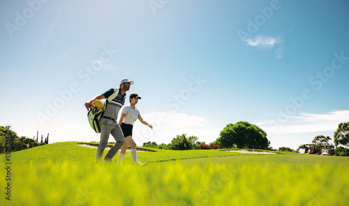 Woman golfer and caddy walking across the golf course during a competition