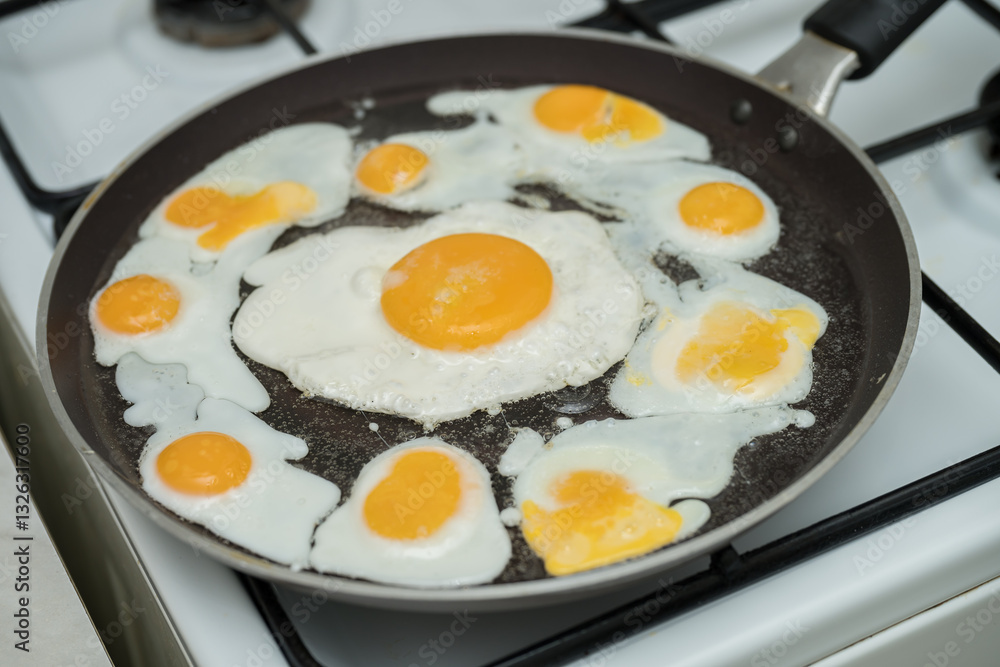 Chicken egg and 9 quail eggs in frying pan.
