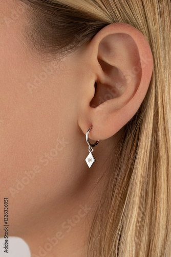 Close-up of female caucasian ear with elegant silver earring. Jewelry catalog. 