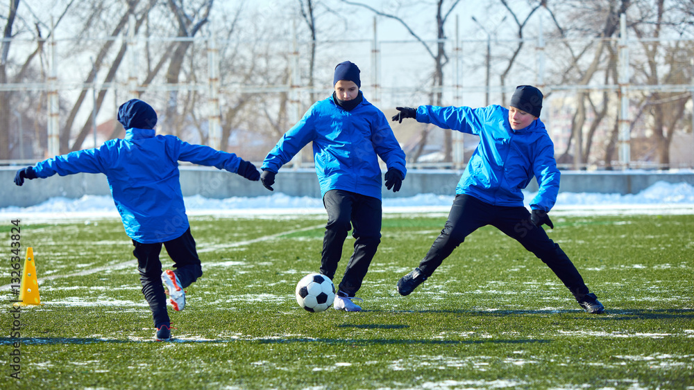 Obraz premium Youth football team practicing movement strategy, positioning, and teamwork on cold outdoor field. Learning and discipline. Concept of competition, sport, training, coaching, fitness.