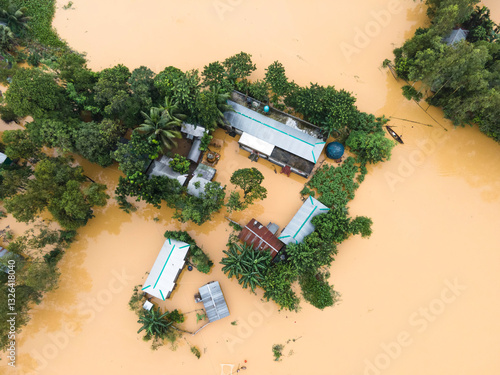 Aerial view of a flooded village with houses surrounded by water and lush greenery, Jhenaigati, Sherpur, Bangladesh. photo