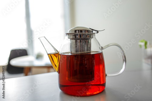 Fotografie Freshly brewed tea in a glass kettle on a kitchen countertop at midday