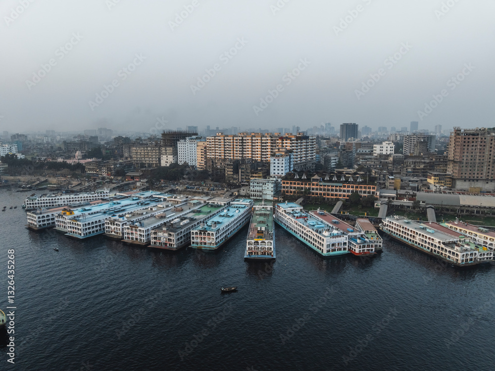 Aerial view of the bustling cityscape along the Buriganga River with modern buildings and boats, Subhadya, Keraniganj, Dhaka, Bangladesh. Aerial view of the bustling cityscape along the Buriganga River with modern buildings and boats, Subhadya, Keraniganj, Dhaka, Bangladesh.