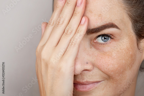 Woman's face with freckles or age spots. Age spots on the face, melasma. Beautiful blue eye close up photo
