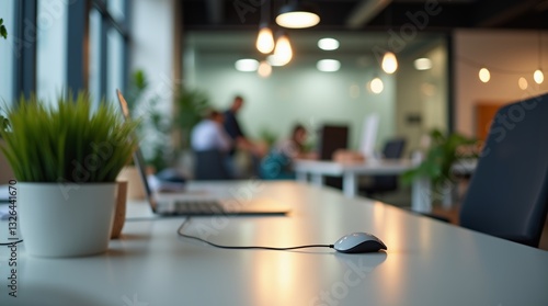 Wallpaper Mural Modern Office Space: A view of an office desk with a computer mouse, laptop, and plant, blurred background, with colleagues working Torontodigital.ca