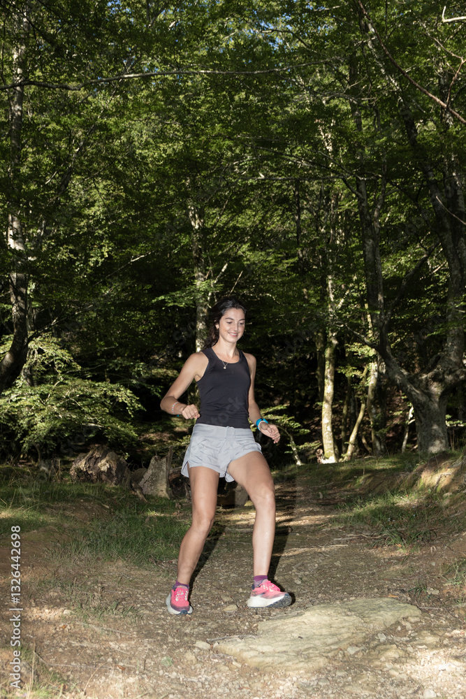 A young woman enjoys trail running through a lush green forest, wearing athletic gear and pink running shoes, surrounded by trees and natural scenery A young woman enjoys trail running through a lush green forest, wearing athletic gear and pink running shoes, surrounded by trees and natural scenery