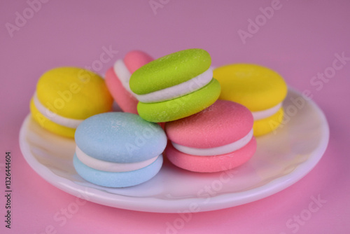 Macaron shaped candies on a white plate. Close-up.
