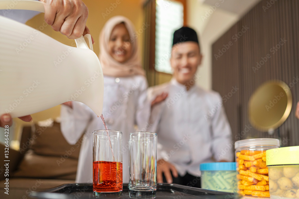 Portrait of the Indonesian Muslim mother serving a drink for the whole family while celebrating Eid Mubarak. Concept of Happy Lebaran, Eid Al Fitr, Idul Fitri, and Ramadan Mubarak celebration Portrait of the Indonesian Muslim mother serving a drink for the whole family while celebrating Eid Mubarak. Concept of Happy Lebaran, Eid Al Fitr, Idul Fitri, and Ramadan Mubarak celebration