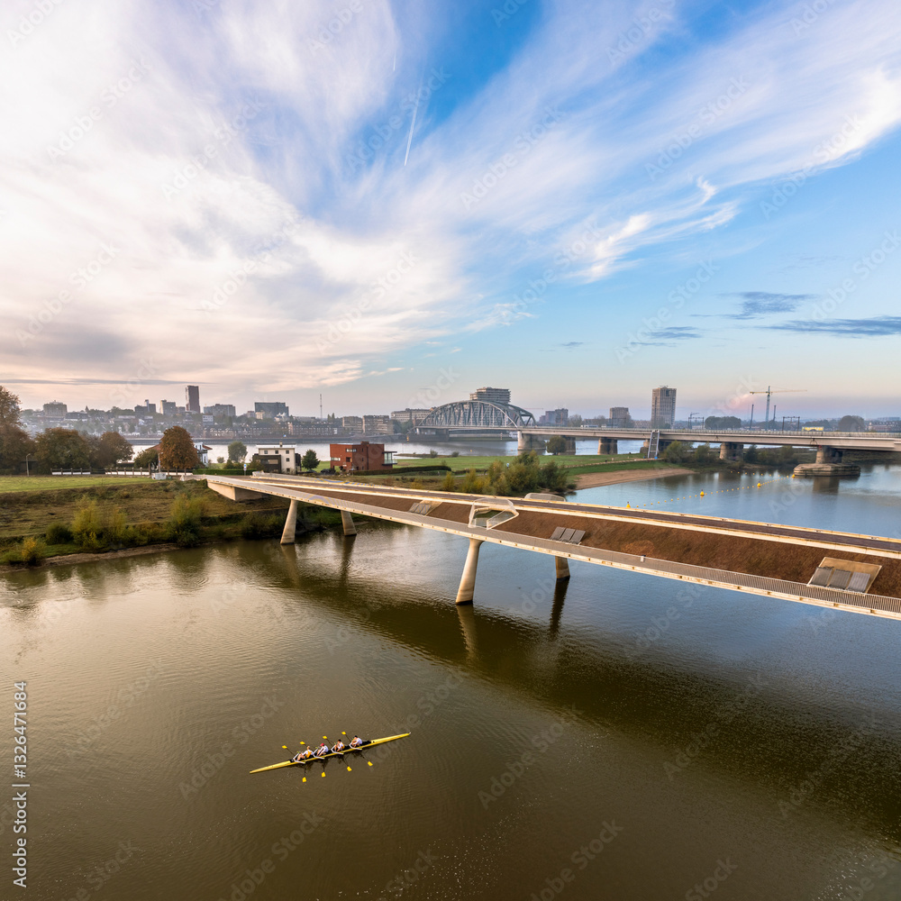 Aerial view of the serene Waalbrug bridge over the tranquil Waal river with boats and a beautiful cityscape, Nijmegen, Gelderland, The Netherlands. Aerial view of the serene Waalbrug bridge over the tranquil Waal river with boats and a beautiful cityscape, Nijmegen, Gelderland, The Netherlands.