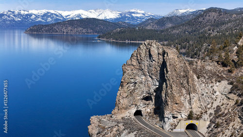 Aerial view of picturesque Cave Rock and tranquil Lake Tahoe surrounded by majestic mountains and a winding road, Lincoln Park, Glenbrook, Nevada, United States.