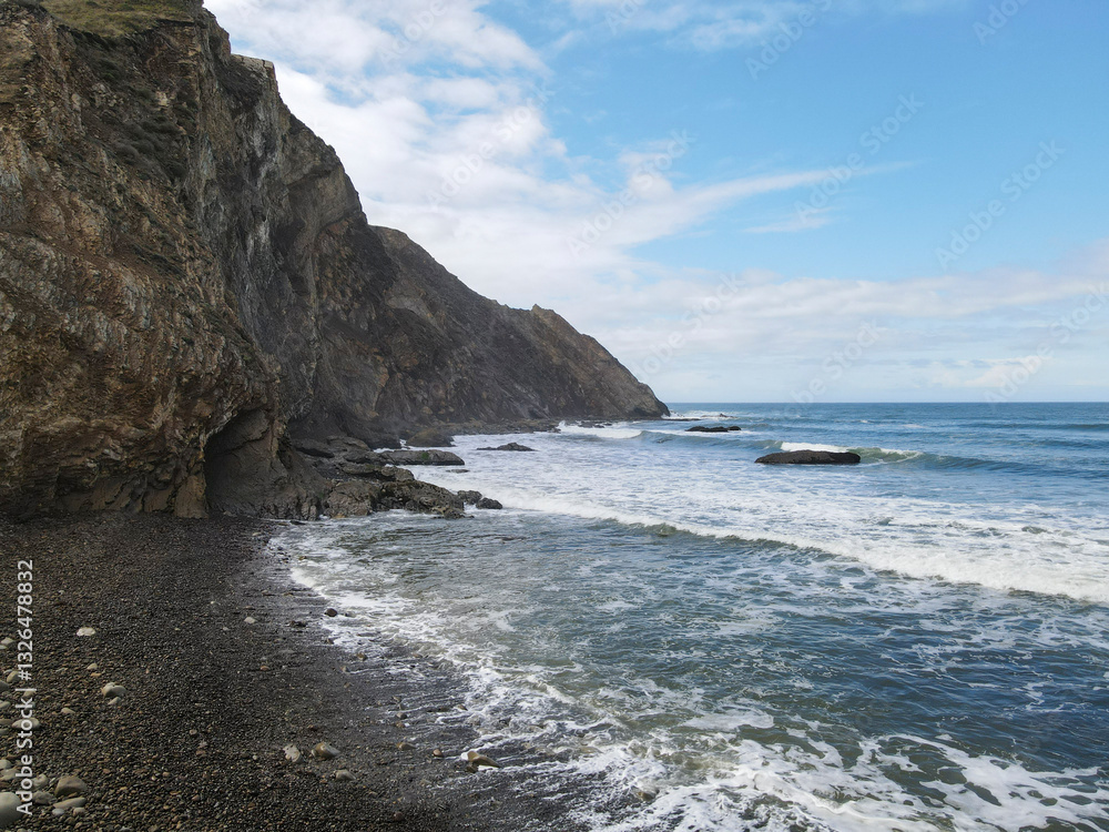 Aerial view of rugged cliffs and tranquil ocean waves along the picturesque Pacific Coast, Point Arena, California, United States. Aerial view of rugged cliffs and tranquil ocean waves along the picturesque Pacific Coast, Point Arena, California, United States.