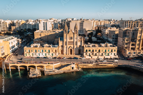 Aerial view of the historic parish church of our lady of mount carmel and carmelite church along the picturesque coastline, St. Julian's, Malta.
