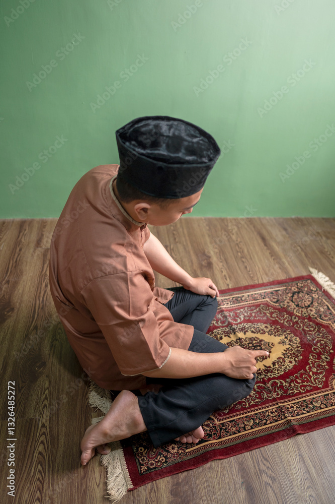 Fototapeta premium Portrait of an Indonesian muslim man praying (salat) at home. Concept of Islamic praying or Ramadan Kareem