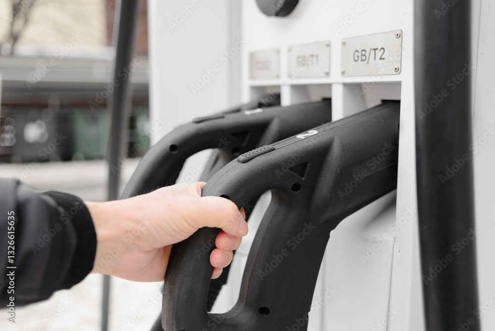 A white man uses a charging station for electric cars. Close-up photo. A white man uses a charging station for electric cars. Close-up photo.
