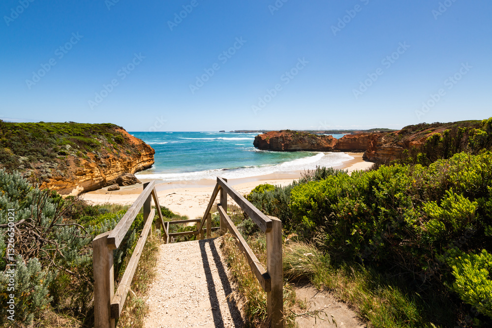 Steps down to sandy cove with headlands. blue sky and blue sea