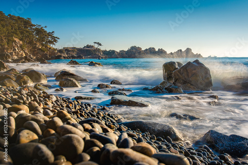 Coast of Korea with rock formations, a long exposure sea with breaking waves at sunrise with some vegetation on the shore