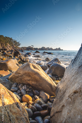 Rocky beach in Korea on the sea of Japan with big round rocks in the foreground and a clear blue sky at sunrise