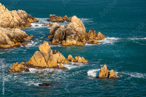 Rocky cliffs of a sea shore in Korea with foamy waves hitting the rocks