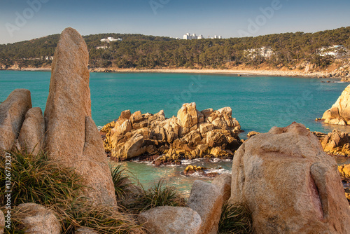 Rocky cliffs of the Korean sea coast with sunny weather at sunrise and a clam turquoise sea