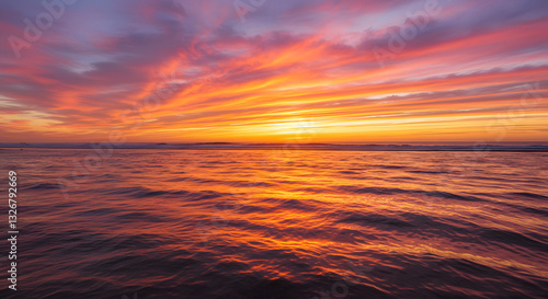 A stunning sunset over the ocean, with warm orange and pink hues reflecting on the water.