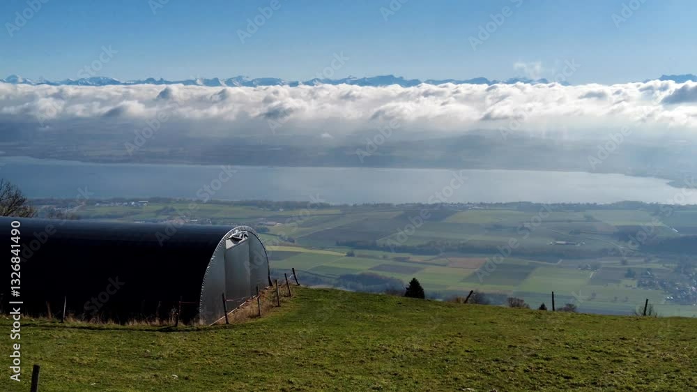 Panoramic panning view from the Jura Mountains near Yverdon, Switzerland. Features a lake, patchwork fields, a stunning cloud inversion and Alps. Ideal for travel, nature, or scenic landscape.