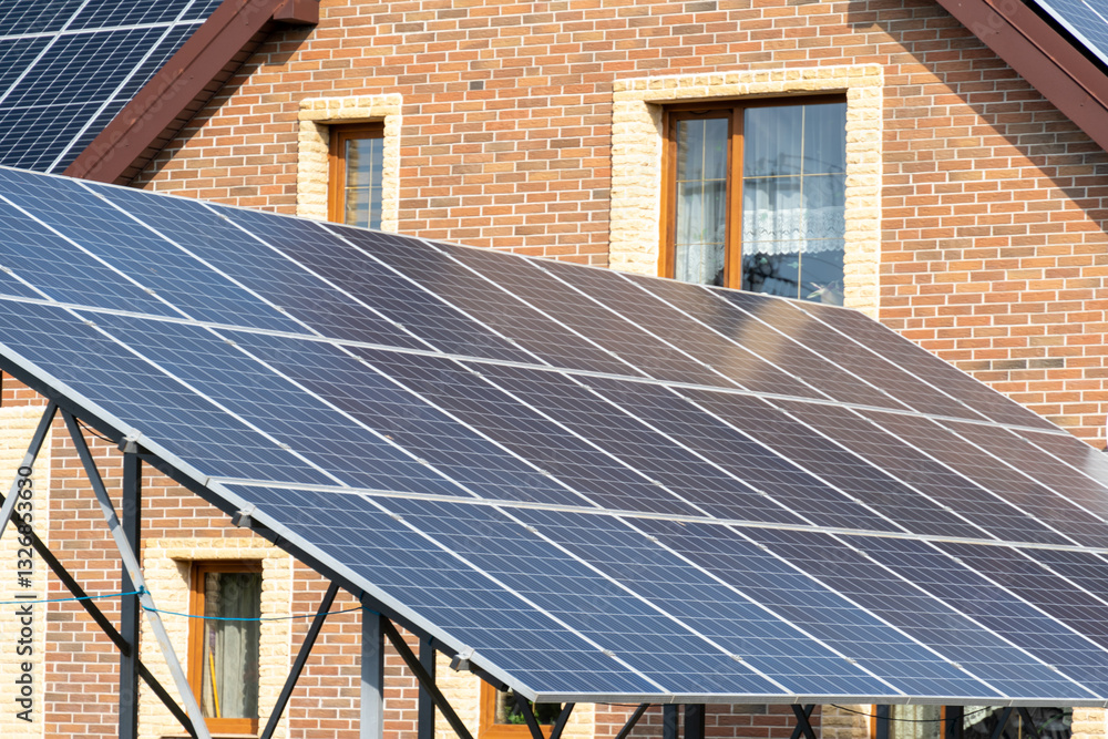 Fototapeta premium Solar panels on a sloped roof are positioned against a brick house, showcasing the adoption of clean energy solutions in modern living spaces