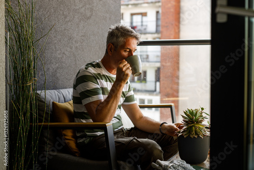 Photo of a man replanting plants on the balcony of loft apartment