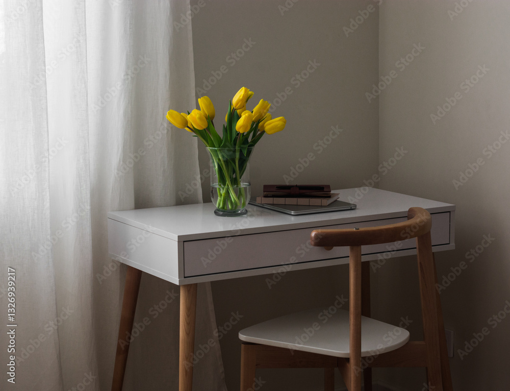 A cozy workplace - a bouquet of yellow tulips, a laptop, a notebook on a white table A cozy workplace - a bouquet of yellow tulips, a laptop, a notebook on a white table