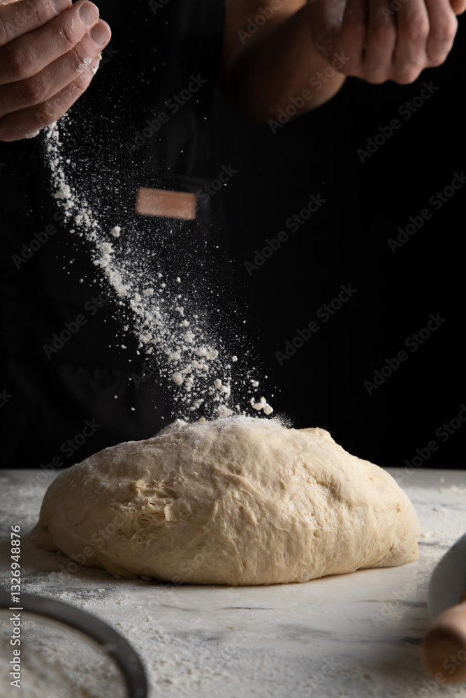 Fototapeta premium Male hands making dough for pizza, bread, pasta. Cooking bread. Kneading the Dough. Isolated on dark background. Copy space, production of flour products