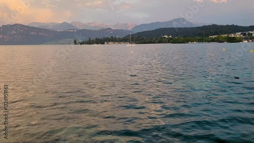 Sailboat in distance crossing Lake Lucerne at sunset