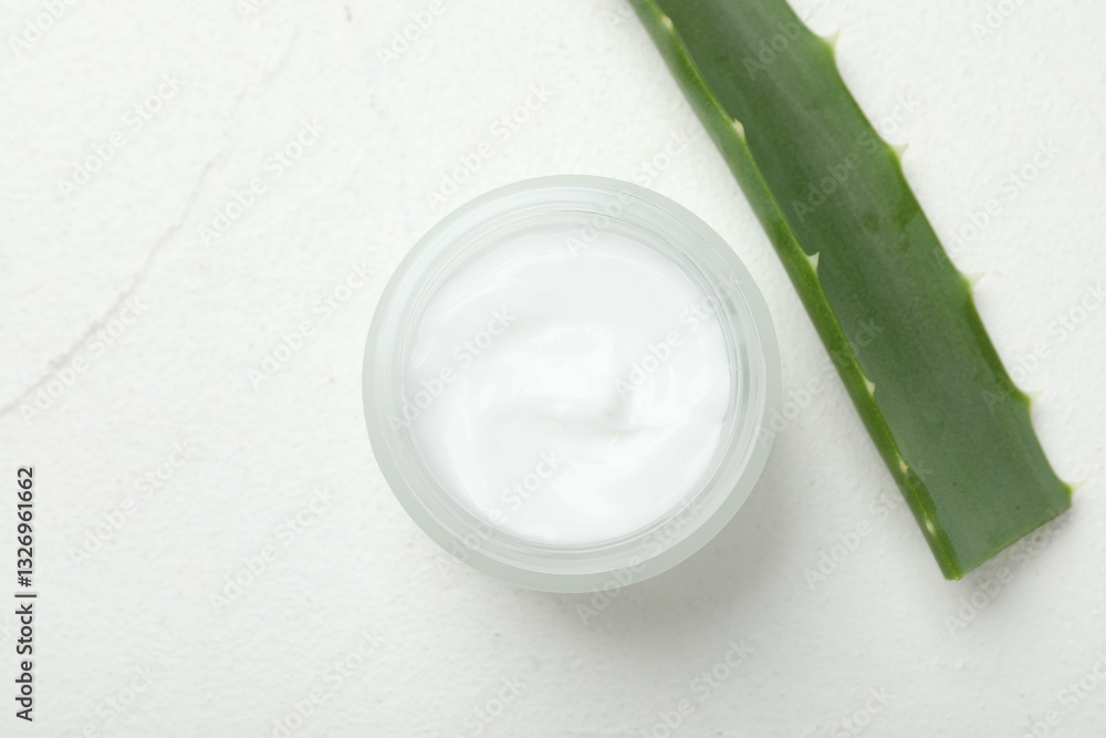 Cream and aloe leaves on white textured background, top view. Space for text Cream and aloe leaves on white textured background, top view. Space for text