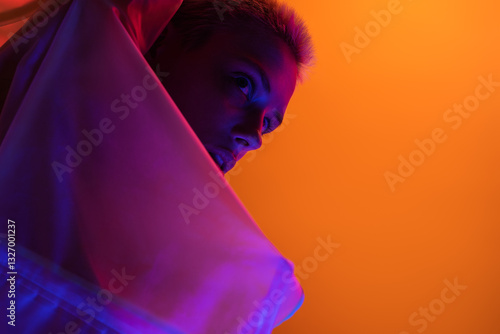 A futuristic art-inspired image of a woman illuminated by neon lights against a vivid orange backdrop.