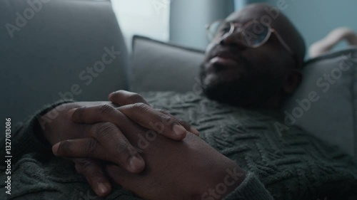 Selective focus shot of Black man with glasses gesticulating speaking about his past experiences when lying on couch during mental health consultation