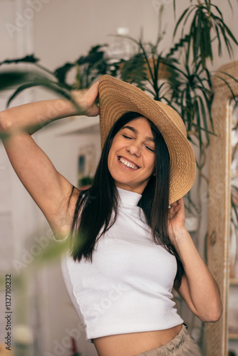 Portrait of a happy young dark-haired woman in a straw hat in a room with indoor plants.Summer concept.
