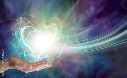 Male healer sending love vibes - distant healing theme with a male open palm and a wispy heart shaped energy ball against a beautiful misty energy background with copy space for spiritual message
